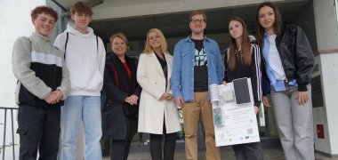 Esra Yılmaz, Lisa Blessenohl, Leonhard Frank und David Vettel übergeben vor dem Haupteingang des Landratsamtes Claudia Bolte, Corinna Simeth und Alexander Uhl vom Klimaschutzteam des Kreises Bergstraße die im Praxisworkshop gebaute Messstation.