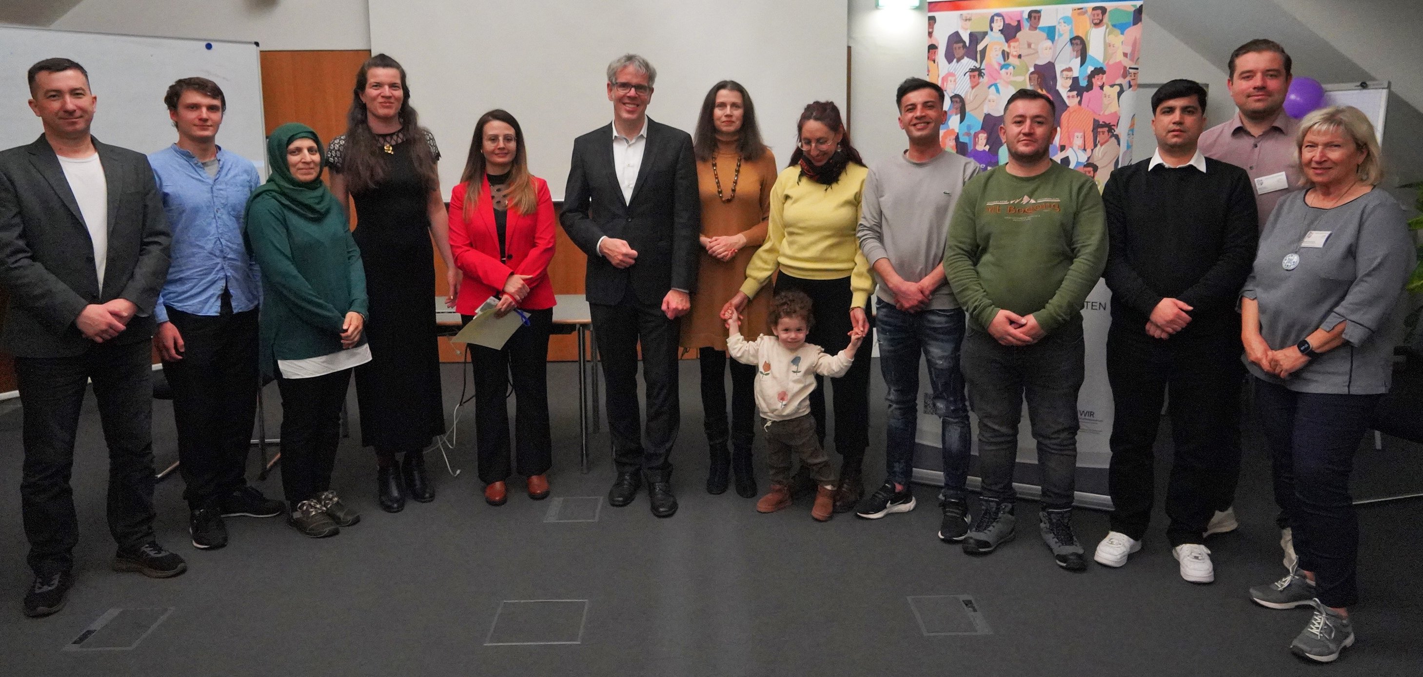 Die neuen Integrationslotsen und -lotsinnen des Kreises Bergstraße stehen mit Landrat Christian Engelhardt, Viktoriya Ordikhovska, Monika Bauer-Herzog und Vitali Dück von der Stabsstelle Integrationsbeauftragte des Kreises Bergstraße sowie Agnes-Csilla Magyar vom Jugendamt und ehemalige Mitarbeiterin bei der Stabsstelle in einem Besprechungssaal nebeneinander.