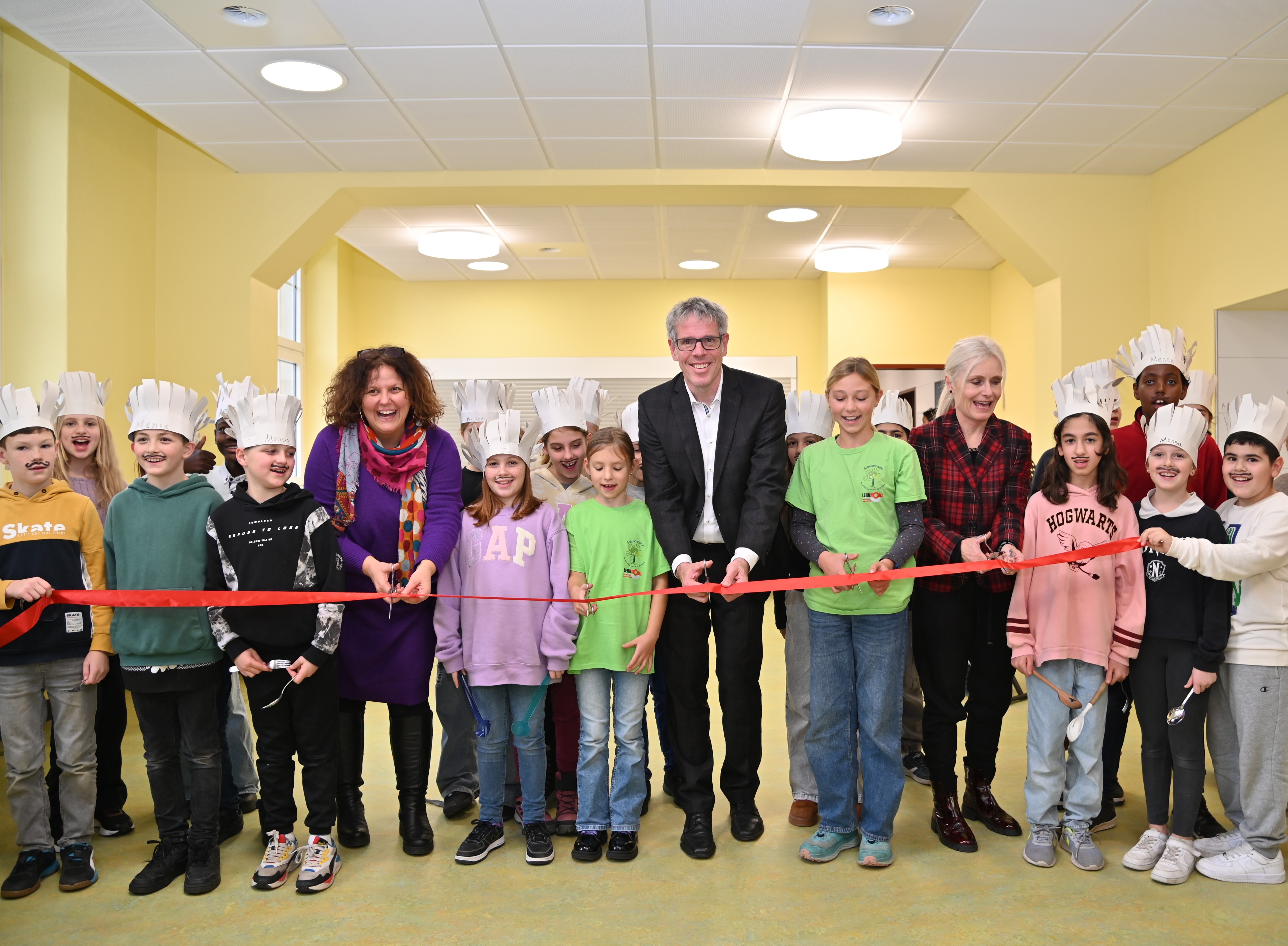 Die Schulleiterin Stefanie Brand, Landrat Christian Engelhardt, die Betreuungsleiterin Stefanie Stephan und die kleinen „Hilfsköche“ der Schillerschule Viernheim haben das rote Band zur Eröffnung der neuen Mensa zerschnitten.