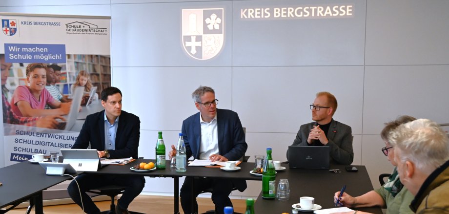 Landrat Engelhardt sitzt gemeinsam mit Johannes Kühn, Technischer Betriebsleiter und Simon Menden, Kaufmännischer Betriebsleiter, in einem Besprechungssaal des Landratsamtes und stellt den Wirtschaftsplan 2025 vor.