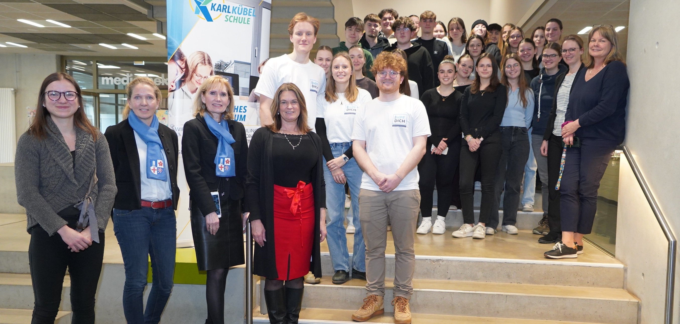Das Bergsträßer Präventionsteam sowie die Erste Kreisbeigeordnete und Gesundheitsdezernentin Angelika Beckenbach steht mit den teilnehmenden Schülerinnen und Schüler der 12. Jahrgangsstufe der KKS sowie den Referentinnen und Referenten in der Schule auf einer Treppe.