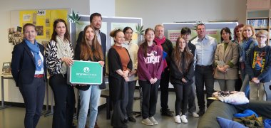 Nadja Niestroj vom Präventionsteam des Kreises, Nicole Brosé und Nikita Girard von der AWO PRISMA Suchthilfe, der Leiter der Martin-Buber Schule Tobias Diehl, die Präventionslehrerin der Martin-Buber-Schule Julia-Maria Pavic, der hauptamtliche Kreisbeigeordnete Matthias Schimpf, der Facharzt für Innere Medizin und Notfallmedizin Heiko Mikkat, Maren Siepmann und Beate Völker von der Landesärztekammer sowie Reinhild Zolg vom Präventionsteam des Kreises stehen vor der Ausstellung an der Martin-Buber-Schule.