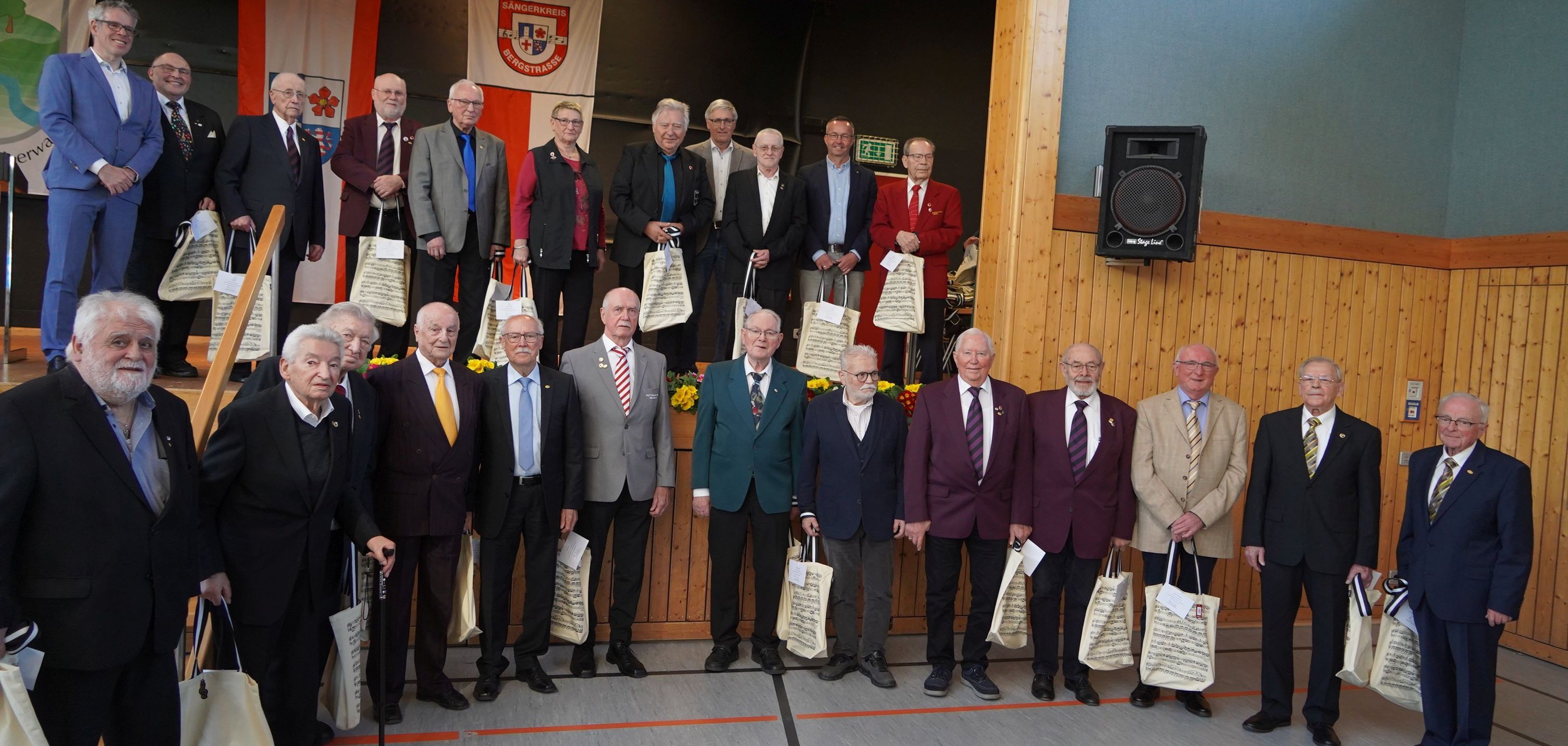 Die Geehrten des Sängerkreises Bergstraße stehen auf und vor der Bühne.