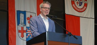 Landrat Christian Engelhardt steht auf der Bühne hinter einem Rednerpult und begrüßt die Anwesenden.