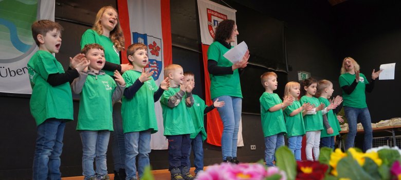 Die Kinder des Waldkindergartens „Wirbelwind“  stehen auf der Bühne und singen.