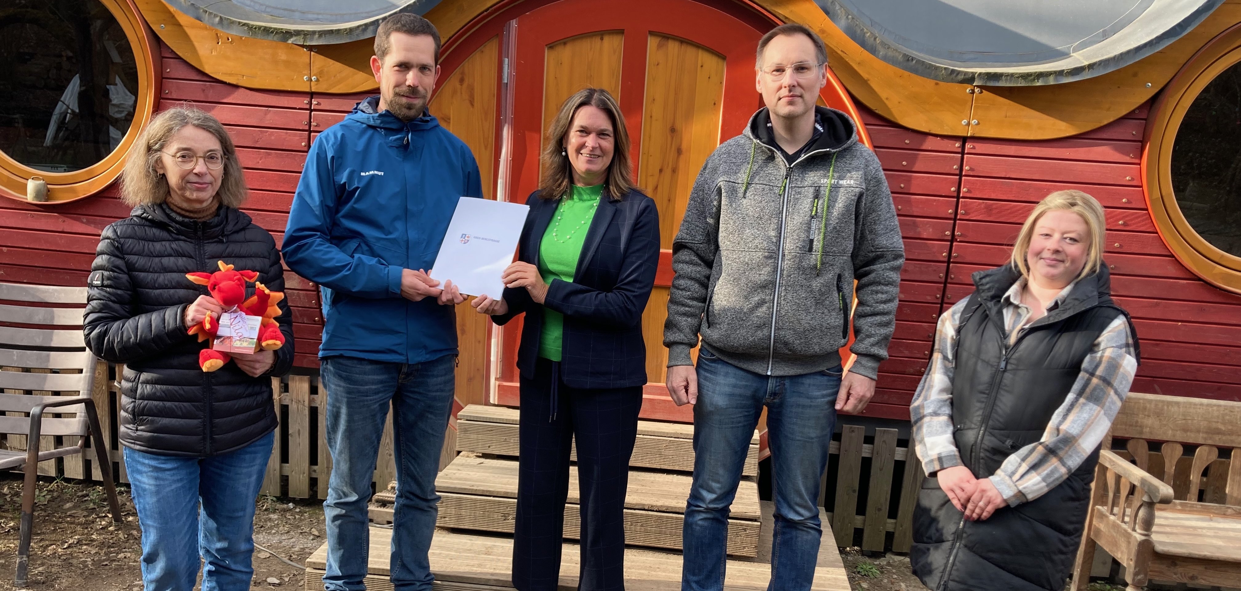 Die Erste Kreisbeigeordnete und Jugenddezernentin Angelika Beckenbach überreicht gemeinsam mit der Fachbereichsleitung Zentrale Steuerung und Finanzmanagement des Jugendamtes des Kreises Bergstraße, Melanie Futterer, den Förderbescheid aus dem Landesinvestitionsprogramm an den ersten Kassenwart der Elterninitiative Birkenauer Sonnenkinder e.V., Ulrich Götz-Heimberger, den zweiten Kassenwart Alexander Vonderschmidt sowie die Beisitzerin Sina Olbrich.