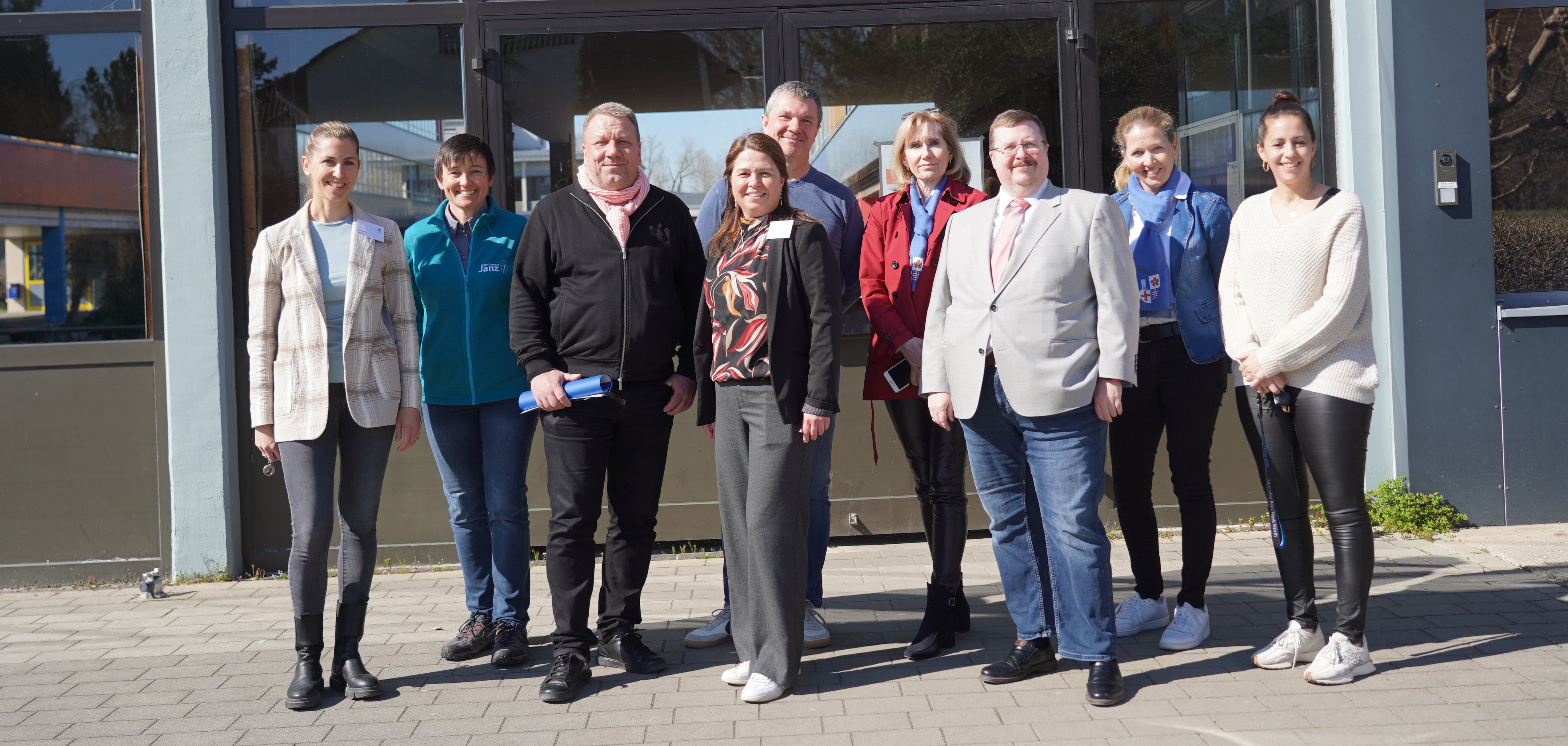 Der hauptamtliche Kreisbeigeordnete Matthias Schimpf, Lehrerin Susanne Schmidt, die Inhaberin des Sanitätshauses Janz, Claudia Schreiber, Konrektorin Petra Popp, der amtierende Präsident des Rotary Clubs Lampertheim, Rüdiger Engert, Reinhild Zolg vom Präventionsteam des Kreises Bergstraße, Schulleiter Sebastian Kuhn, Nadja Niestroj vom Präventionsteam des Kreises Bergstraße und Lehrerin Angelika Burkhard stehen vor dem Eingang der Alfred-Delp-Schule in Lampertheim.