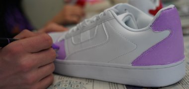 Ein Jugendlicher bemalt einen Schuh.