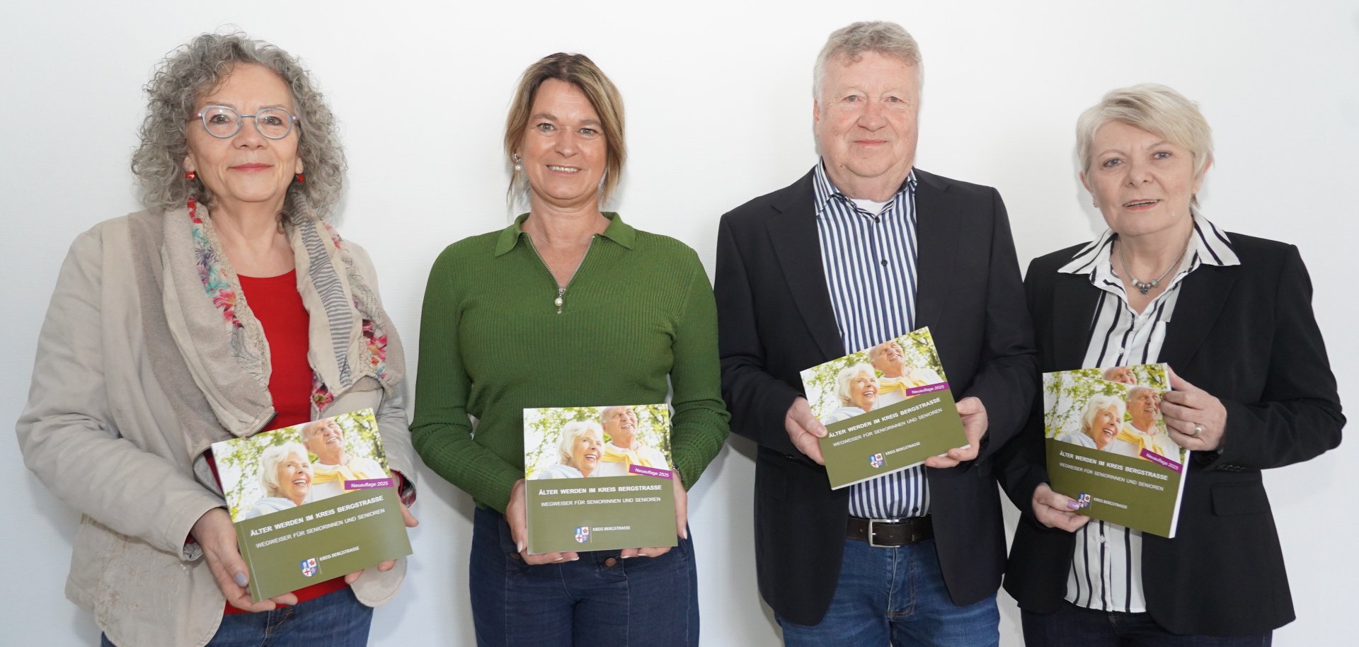 Die Erste Kreisbeigeordnete Angelika Beckenbach steht mit Martina Zwecker (Fachstelle Leben im Alter des Kreises Bergstraße) sowie Fred Müller und Angelika Koch (Verlag „Verlag & Marketing“) nebeneinander vor einer weißen Wand und halten jeweils ein Exemplar der neunten, überarbeiteten und ergänzten Auflage des Seniorenwegweisers des Kreises Bergstraße in den Händen.