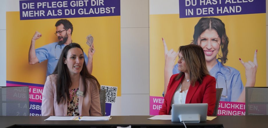 Die Erste Kreisbeigeordnete und zuständige Dezernentin Angelika Beckenbach sitzt neben Christina Arnold von der Fachstelle Leben im Alter vor zwei Aufstellern der Pflegekampagne 2024 des Kreises Bergstraße und stellt den Abschlussbericht vor. 