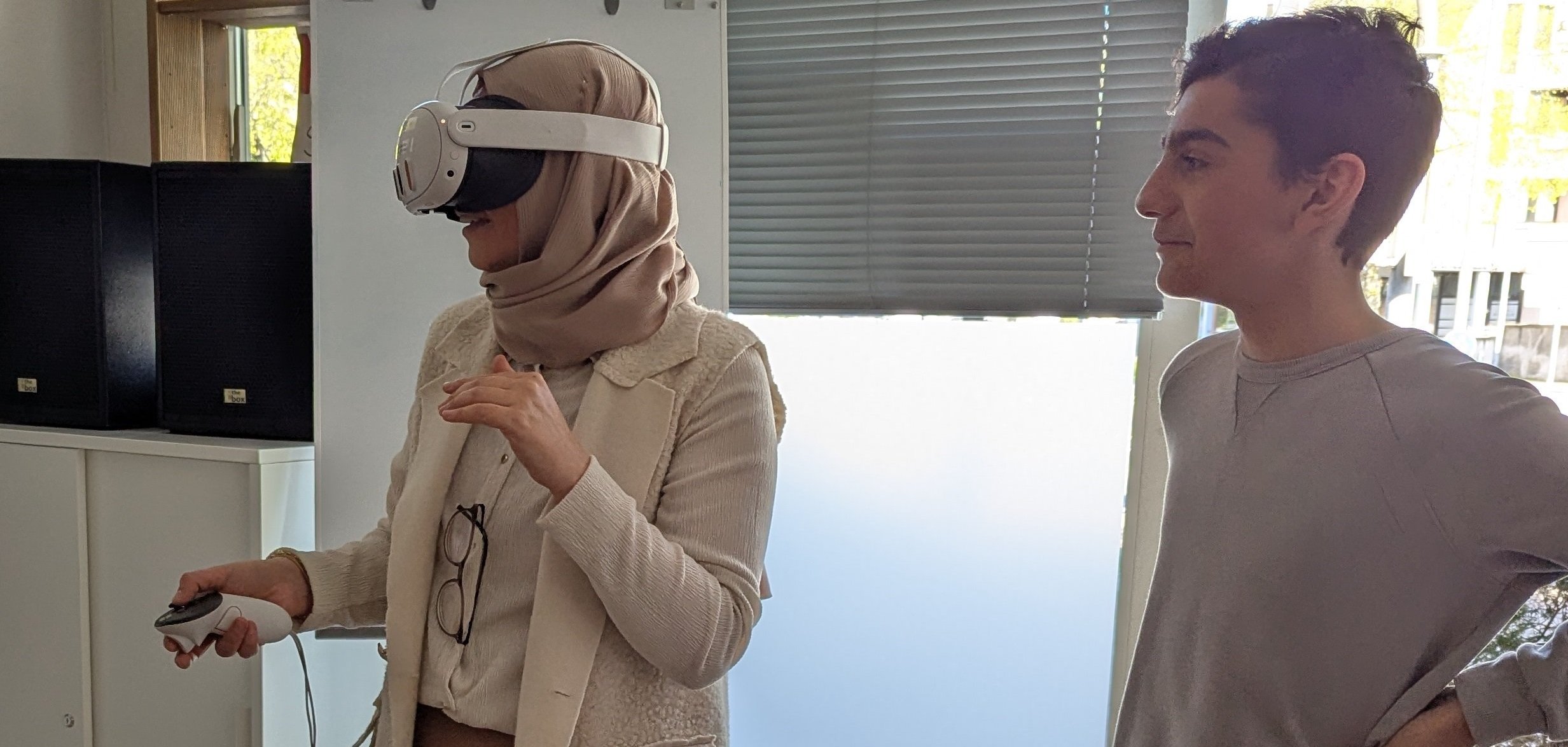 Zwei teilnehmende Jugendliche stehen nebeneinander, eine der beiden trägt eine VR-Brille.