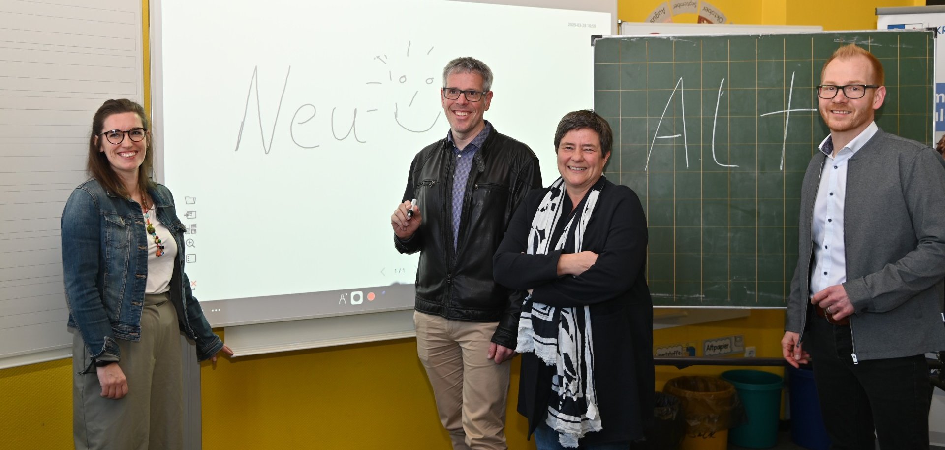 Die IT-Beauftragte der Schillerschule Lampertheim, Nina Hoffmann, Landrat Christian Engelhart, Schulleiterin Annette Wunder-Schönung und der Technische Betriebsleiter des Eigenbetriebs Schule und Gebäudewirtschaft, Johannes Kühn stehen vor einer digitalen sowie Kreidetafel.