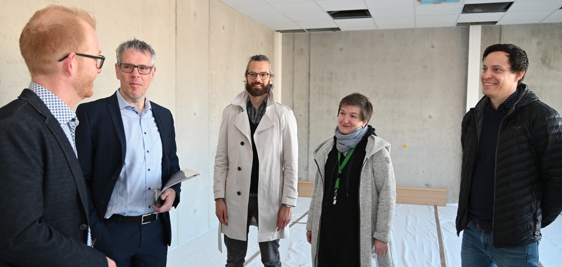 Der Technische Betriebsleiter des Eigenbetriebs Schule und Gebäudewirtschaft, Johannes Kühn, Landrat Christian Engelhardt, der Schulleiter, Timo Helwig-Thome, die stellvertretende Schulleiterin Nora Snaschel und der Kaufmännische Betriebsleiter des Eigenbetriebs stehen auf der Baustelle des Neubaus der Schule in den Weschnitzauen in Biblis.