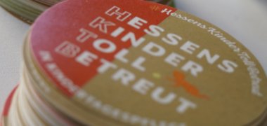 Kreise mit Infos zur Kindertagespflege liegen gestapelt auf einem Tisch.