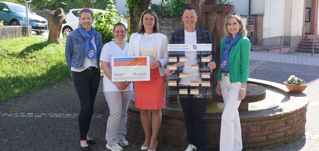 Erste Kreisbeigeordnete und Gesundheitsdezernentin Angelika Beckenbach (Mitte) und das Präventionsteam des Kreises Bergstraße (Reinhild Zolg, rechts, und Nadja Niestroj, links) hält zusammen mit der Fachärztin für Allgemeinmedizin, Dr. med. Aylin Büttner (2. v.l.) einen großen Organspende-Ausweis, während der Bürgermeister der Gemeinde Abtsteinach, Sven Bassauer (2. v.r.) die zehnte Organspende-Ausweis-Tafel hält.
