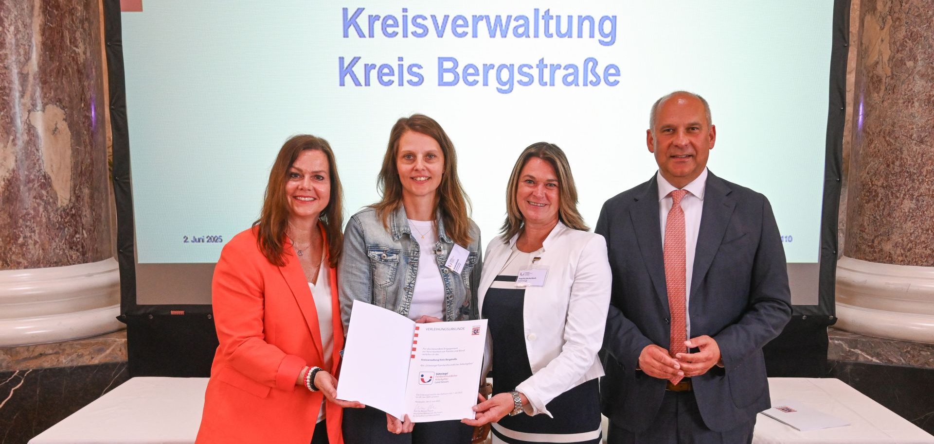 Die Erste Kreisbeigeordnete Angelika Beckenbach, die zwei Frauen- und Gleichstellungsbeauftragten des Kreises Alexandra Schmitt und Nicole Schmitt sowie  Staatsminister Prof. Dr. Roman Poseck stehen nebeneinander im Schlos Biebrich.