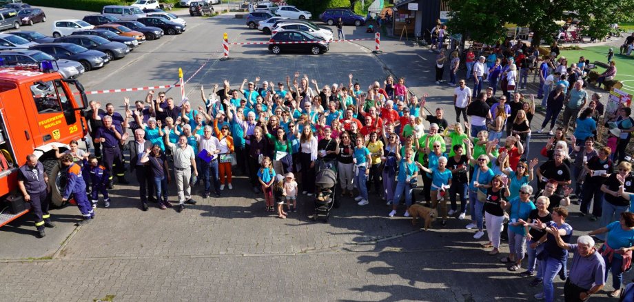 Bewohnerinnen und Bewohner Wahlens präsentieren sich zusammen beim Landesentscheid "Unser Dorf hat Zukunft" und winken.