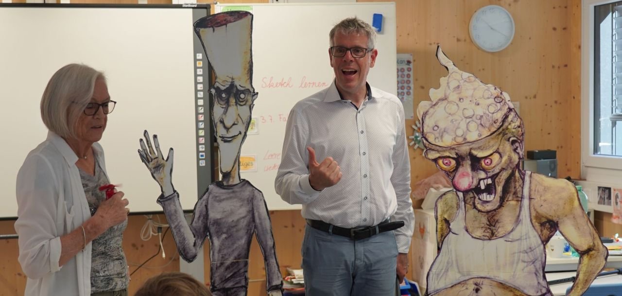 Christian Engelhardt vor Ort beim Workshop zur Suchtprävention von Marlies Wank (links). Die trockene Alkoholikerin veranschaulichte die Gefahren der Sucht mit ihren Giftzwergen „Niko und Alko“, die jeweils links und rechts von Landrat Christian Engelhardt aufgestellt sind.