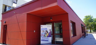 Die sanierte Sporthalle der Astrid-Lindgren-Schule in Bürstadt-Bobstadt in der Außenansicht. Zu sehen ist die neue rote Fassade sowie der neue Eingang über die St-Josef-Straße.