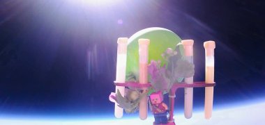 Das Bild zeigt die Versuchsobjekte der Schülerinnen und Schüler am Stratosphärenballon, der gerade durch die Erdatmosphäre schwebt. Im Hintergrund ist die Sonne und ein Teil der Erde zu sehen. Die Versuchsobjekte sind: Ein Legomännchen, eine Pflanze und mehrere Röhrchen mit Flüssigkeiten und anderen Materialien.