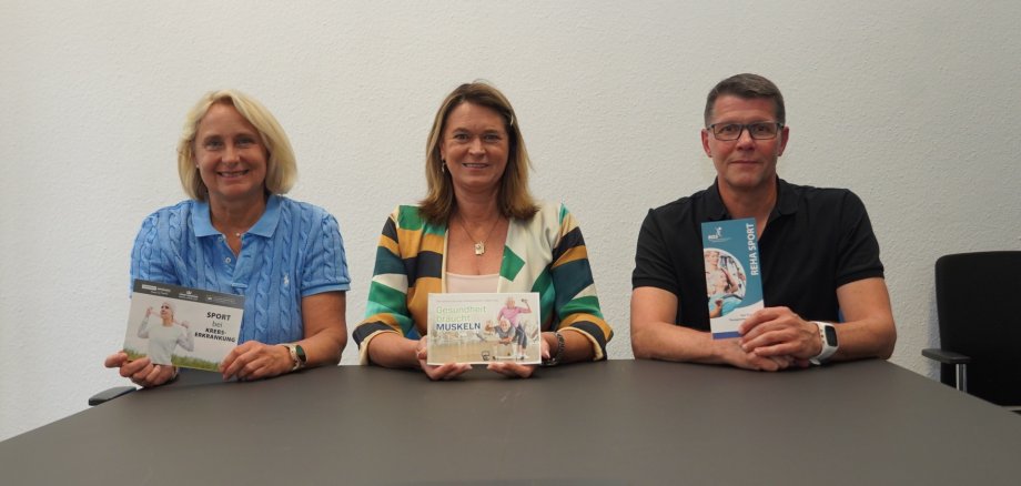 Die Erste Kreisbeigeordnete Angelika Beckenbach (Mitte) informierte zusammen mit Dr. Tanja Lahaye, Fachärztin für Innere Medizin, Hämatologie und Onkologie sowie Medikamentöse Tumortherapie (links) und Christopher Schuff, Sportwissenschaftler, Sporttherapeut und Übungsleiter des Reha-Sports im Sportpark Heppenheim (rechts) über die positive Wirkung von Sport gegen Krebs sowie Onkosport-Angebote im Kreis Bergstraße. Alle halten Flyer zum Onkosport-Angebot in Heppenheim.