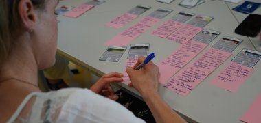 Workshop Eine teilnehmende Person notiert etwas auf einem Zettel.