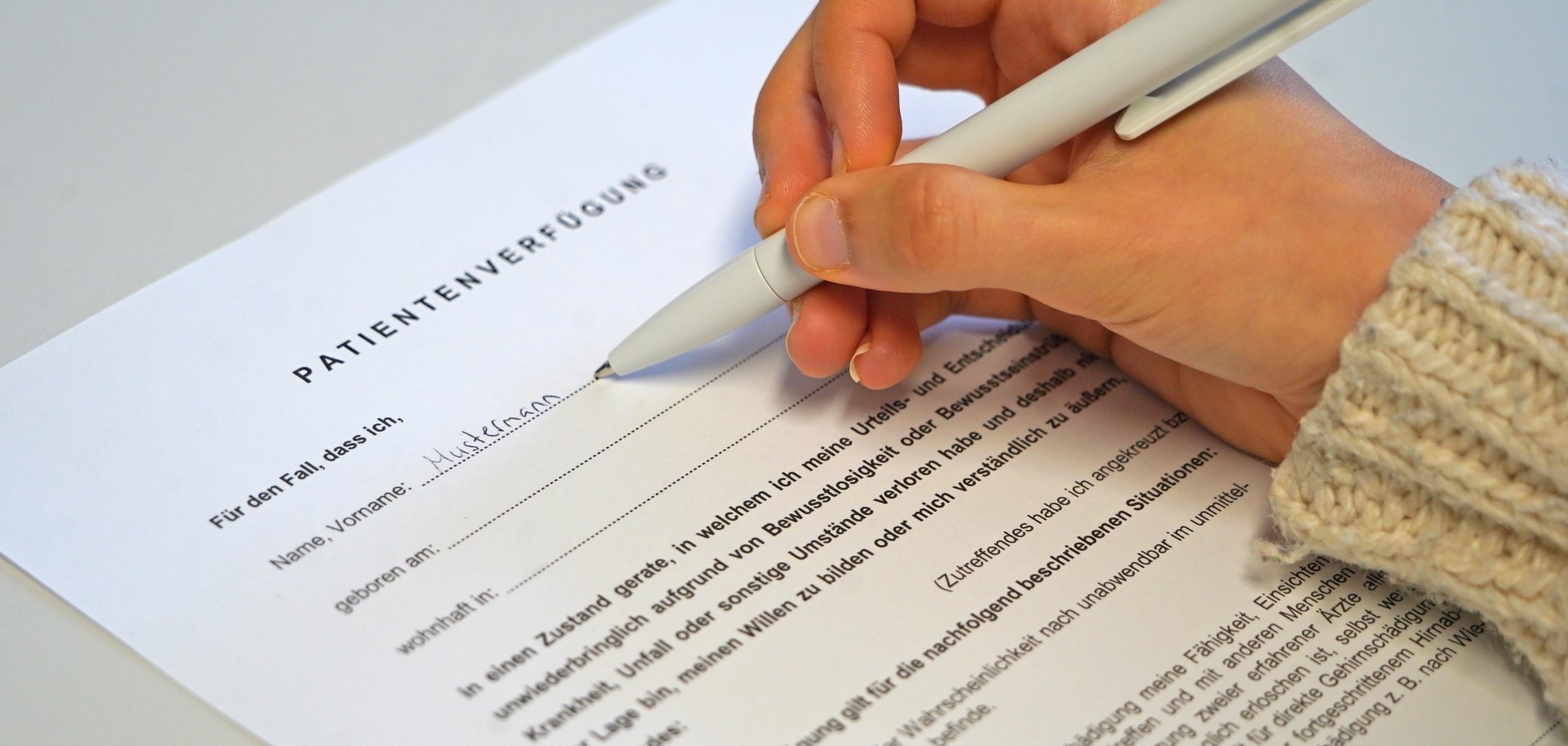 Eine Hand füllt eine Patientenverfügung aus.