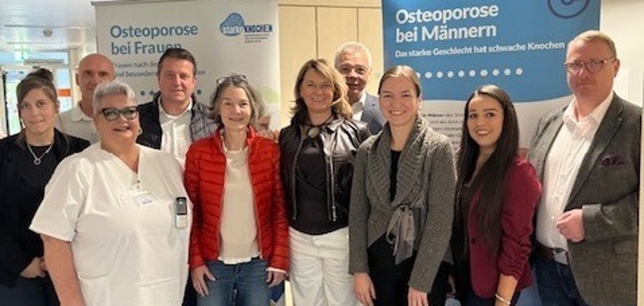 Die Erste Kreisbeigeordnete Angelika Beckenbach (Mitte) klärt zusammen mit (v.l.n.r.) Michaela Weber (PauLa NORIE), Irena Wolf (Leitung Geriatrische Tagesklinik des St. Marien Krankenhauses) in Begleitung von ihrem Mann, Alexander Scholl (designierter Bürgermeister von Lampertheim), Christina Adler-Schäfer (PauLa NORIE), Bürgermeister Gottfried Störmer, Jennifer Jarke (Fachbereichsleitung Gesundheitsversorgung des Gesundheitsamtes), Selina Werner-Celikkan (Referentin der Geschäftsführung des St. Marien Krankenhauses) und Florian Busse (Geschäftsführer des Krankenhauses) über die Knochenkrankheit auf.