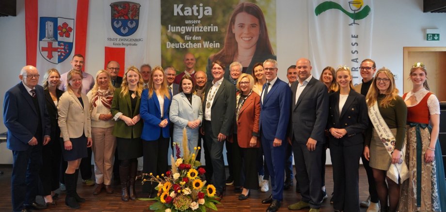 Gruppenbild Bei einem feierlichen Empfang stehen Landrat Christian Engelhardt, Katja Simon und zahlreiche Vertreterinnen und Vertreter der regionalen Politik- und Kulturlandschaft auf einer kleinen Bühne.