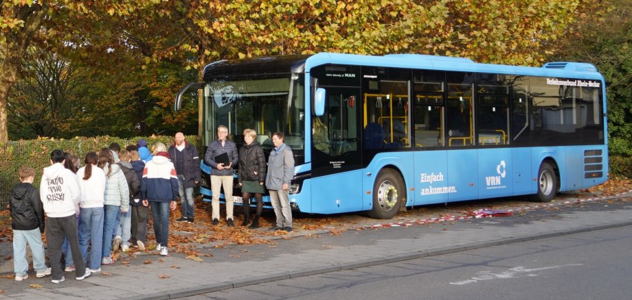 Bei der Busschule am Starkenburg Gymnasium Heppenheim stehen der Teamleiter der DB Regio Bus Mitte, Andreas Klemmer, Landrat Christian Engelhardt, Schulleiterin Katja Eicke und Physiklehrer Stephan Endres mit den Kindern am Bus.