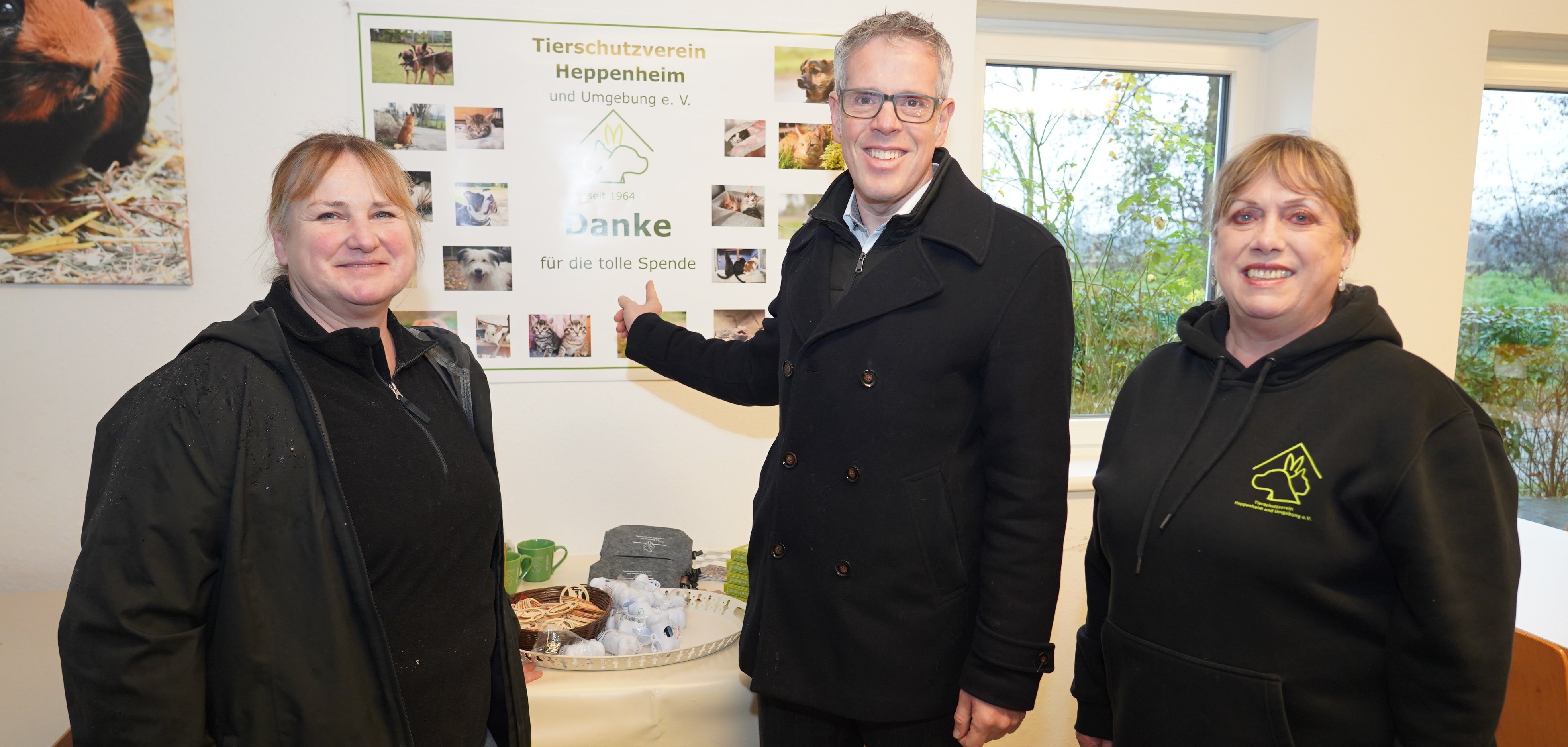 Landrat Christian Engelhardt steht mit der ersten Vorsitzende des Tierschutzvereins Heppenheim und Umgebung, Katrin Hassanin sowie der zweiten Vorsitzenden, Inge Sokoll im Tierheim und zeigt auf ein Spendenschild.