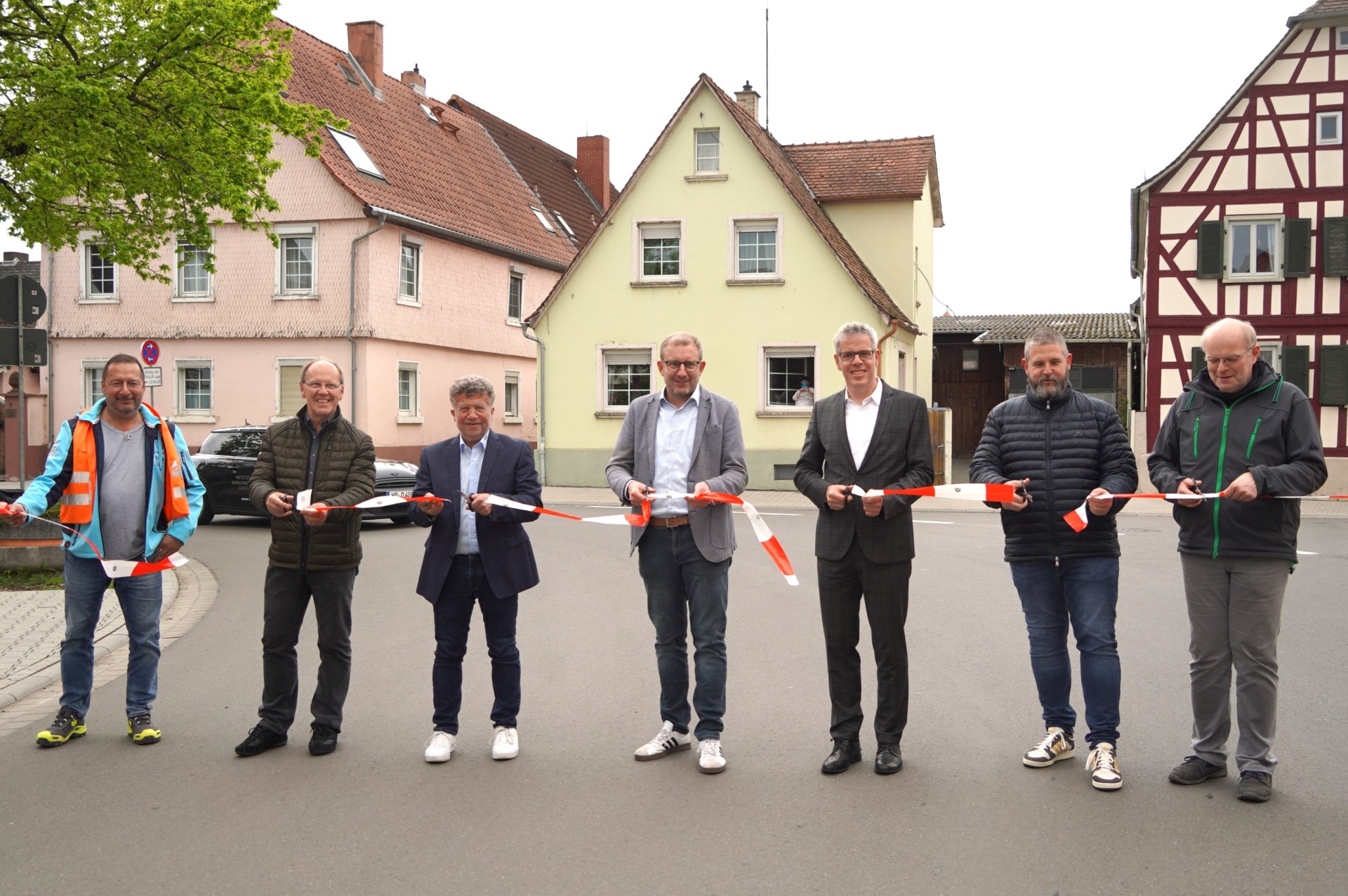 Das Bild zeigt mehrere Männer, die eine Straße für den Verkehr freigeben. Dafür schneiden sie mit einer Schere ein Absperrband durch. Zu sehen sind unter anderem Landrat Christian Engelhardt (3. v. re.) undGroß-Rohrheims Bürgermeister Karsten Krug (4. v. re.). Es handelt sich um die Verkehrsfreigabe der K41 (Kornstraße) in Groß-Rohrheim im April 2025.