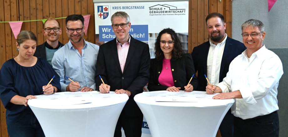 Pakt für den Ganztag Schlossberg- und Schillerschule (v.l.n.r.) Schulleiterin der Schillerschule Auerbach, Sylvia Meier, Technischer Betriebsleiter des Eigenbetriebs Schule und Gebäudewirtschaft, Johannes Kühn, Markus Dehoust Leiter von GaBiBe, Landrat Christian Engelhardt, Nadide Sen-Clausen, Schulleiterin der Schlossbergschule, stellvertretender Kaufmännischer Betriebsleiter, Marc Colin und der Leiter von KuBuS e. V., Thomas Jungfleisch unterschreiben die Dreiecksvereinbarung