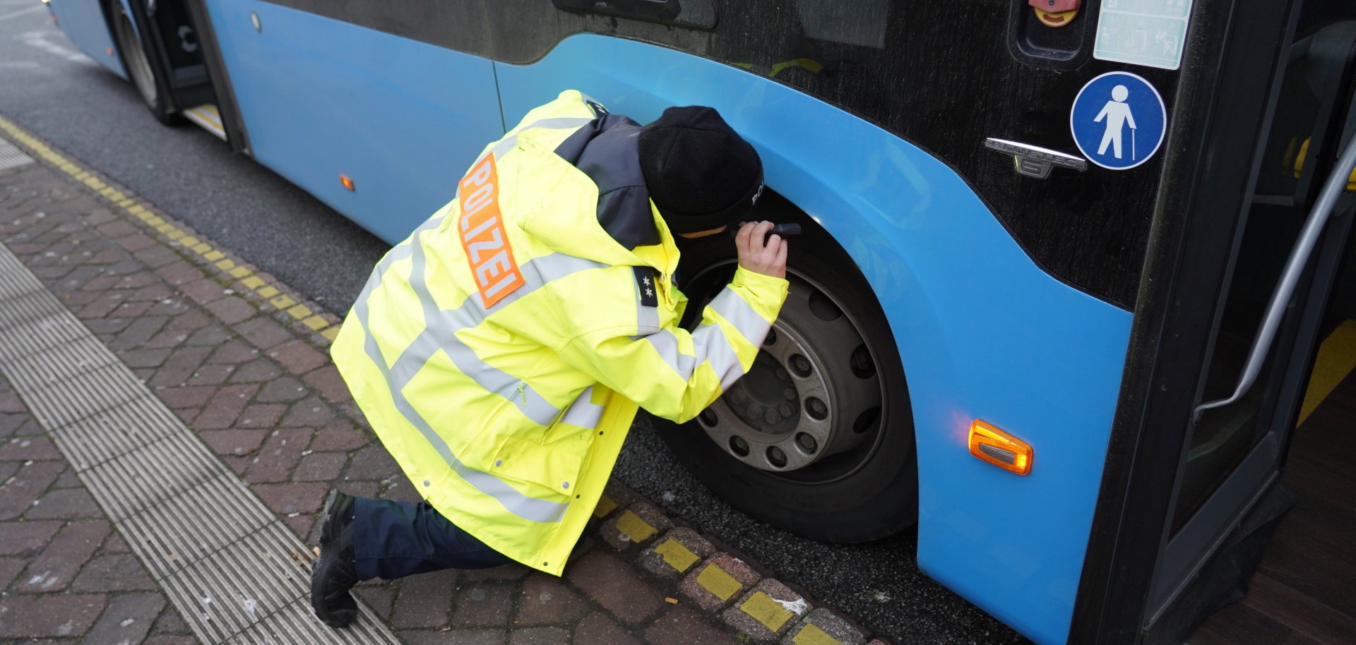 Bus-Kontrollen Ein Polizist beleuchtet die Reifen eines stehenden Busses.
