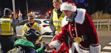 Vergabe Nikoläuse an Schüler Im Kostüm verteilt Landrat Christian Engelhardt gemeinsam mit dem Stadtpolizeibeamten der Stadt Heppenheim, Ahmed Dogan, der Schutzfrau vor Ort, Stephanie Hellermann-von-Serkowsky und dem Leiter der Abteilung ÖPNV und Mobilität des Kreises Bergstraße, Dominik Perleth, Schokonikoläuse an Radfahrende mit korrekter Beleuchtung.