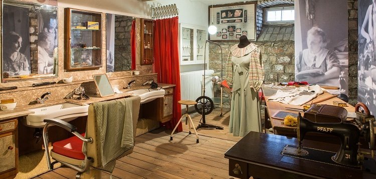 Das Bild zeigt einen Wohnraum des Themenbereiches „Familienleben“. Zu sehen ist unter anderem ein Ausschnitt eines Friseursalons in den 1930er Jahren.