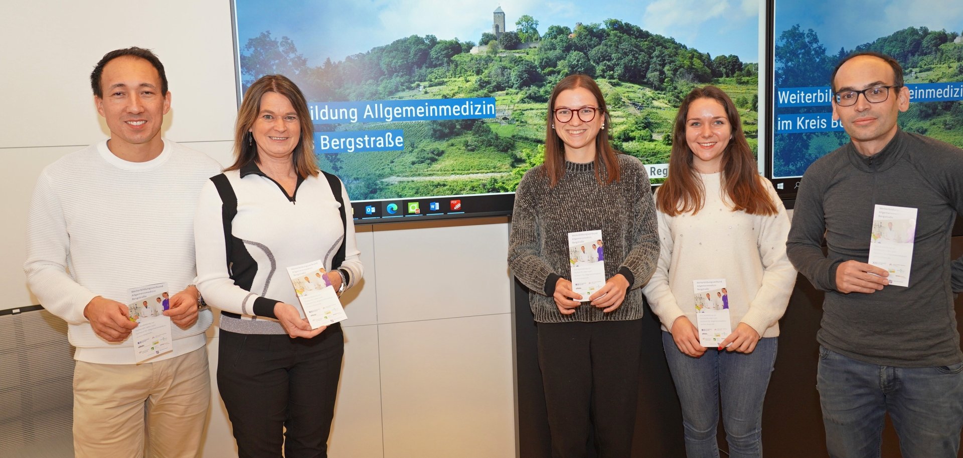 Die erste Kreisbeigeordnete und Gesundheitsdezernentin Angelika Beckenbach steht gemeinsam mit dem Vorsitzenden des Weiterbildungsverbundes Allgemeinmedizin Bergstraße sowie leitenden Ärztlichen Direktor und Chefarzt der Kardiologie des Kreiskrankenhauses Bergstraße, Prof. Dr. Stefan Baumann, dem stellvertretenden Vorsitzenden und hausärztlich tätigen Facharzt für Innere Medizin, Dr. Florian Wagner, der Leiterin des Fachbereichs Gesundheitsversorgung des Kreises Bergstraße, Jennifer Jarke, sowie Sandra Schmitt vom Fachbereich Gesundheitsversorgung, vor einem Bildschirm mit der neuen Website.