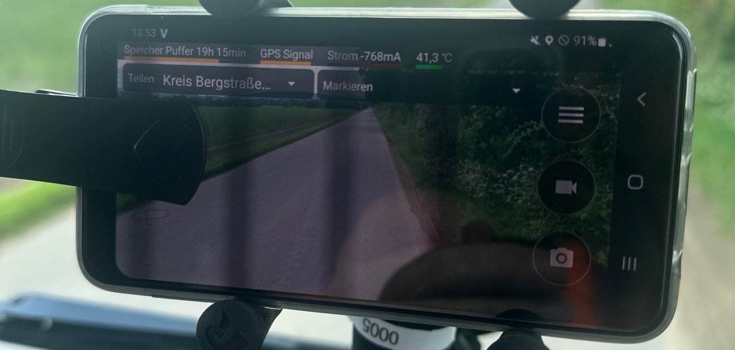 Das Smartphones an der Innenseite der Windschutzscheibe des Müllfahrzeugs.