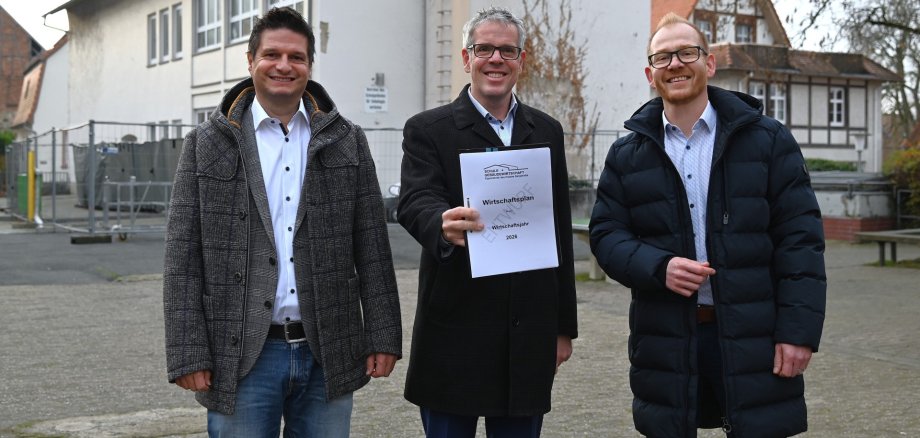 (v. l. n. r.) Der stellvertretende Kaufmännische Betriebsleiter des Eigenbetriebs Schule und Gebäudewirtschaft, Stefan Lienert, Landrat Christian Engelhardt und der Technische Betriebsleiter des Eigenbetriebs Schule und Gebäudewirtschaft, Johannes Kühn, präsentieren das Zahlenwerk (für die Kamera) direkt vor einem laufenden Projekt: dem Umbau der Martin-Buber-Schule in Heppenheim zur integrierten Gesamtschule.