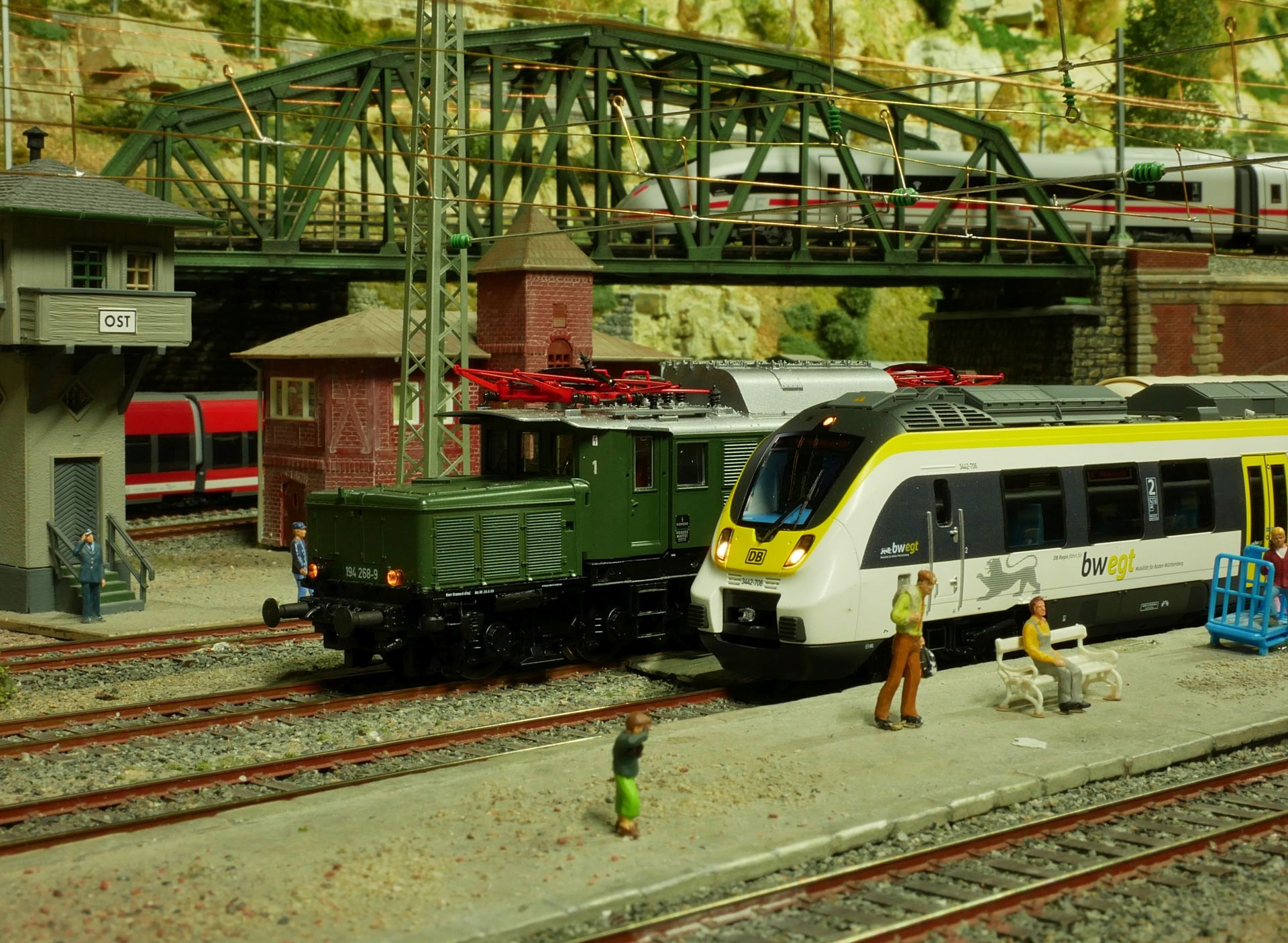 Das Bild zeigt einen Ausschnitt der Modellbahn mit zwei Zügen und kleinen Figuren.
