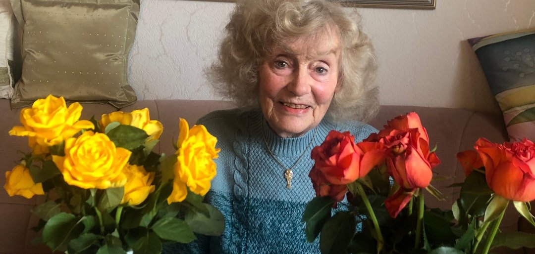Das Bild zeigt Margit Otto in der Mitte, rechts und links von ihr sind Blumen