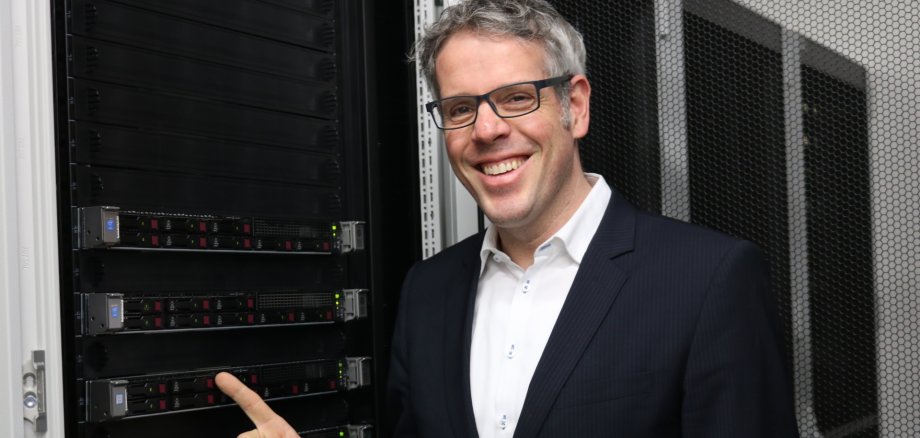 DIGITAL-Award 2026 Landrat Christian Engelhardt steht vor einem Server und zeigt lächelnd drauf.