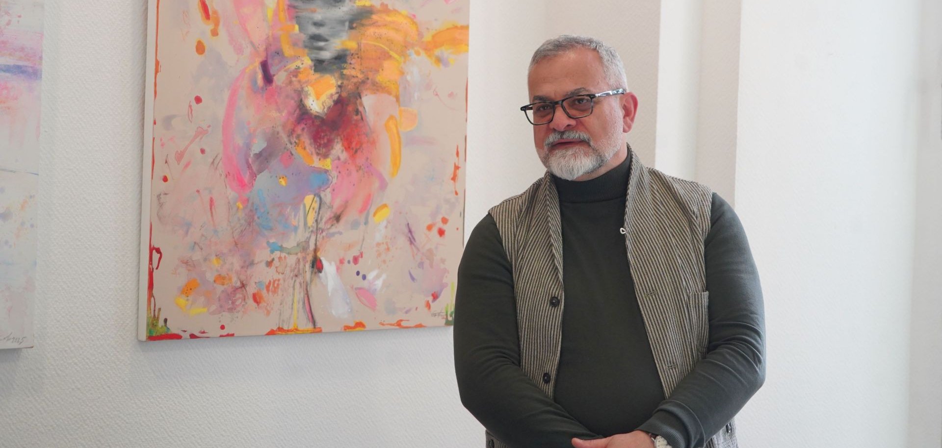 Tigran Grigoryan stellte seine Kunstwerke im Rahmen einer Vernissage näher vor. Er steht neben einer seiner Gemälde.