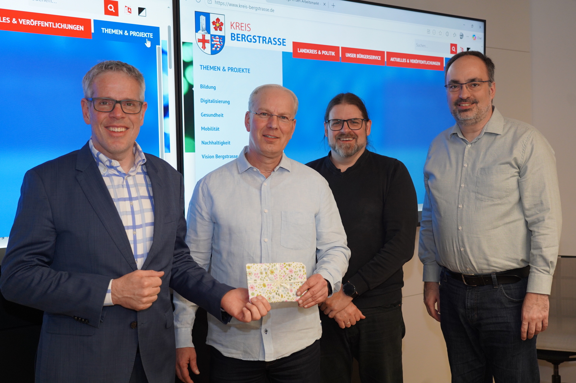 Landrat Christian Engelhardt (links) überreichte zusammen mit Alexander Brendel vom Jobcenter Neue Wege (2. v.r.) und dem Leiter der Abteilung Moderne Verwaltung, eGovernment und IT , Dr. Johannes Bunsch (rechts), ein Gutscheinpaket für einen Kinobesuch an Dirk Filkorn (Mitte), dem Namensgeber des Chatbots.