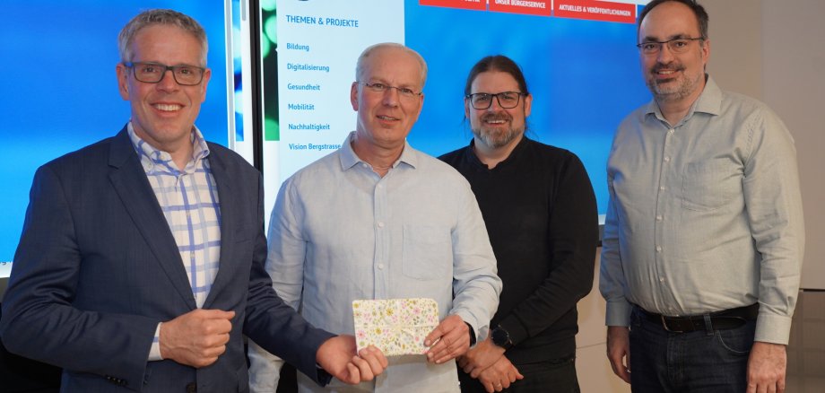 Landrat Christian Engelhardt (links) überreichte zusammen mit Alexander Brendel vom Jobcenter Neue Wege (2. v.r.) und dem Leiter der Abteilung Moderne Verwaltung, eGovernment und IT , Dr. Johannes Bunsch (rechts), ein Gutscheinpaket für einen Kinobesuch an Dirk Filkorn (Mitte), dem Namensgeber des Chatbots.