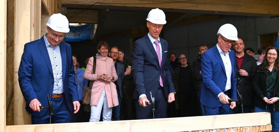 Richtfest Schülerforschungszentrum Südhessen Der Leiter des Schülerforschungszentrums Südhessen Bergstraße, Dr. Thomas Schneidermeier, Hessens Kultusminister Armin Schwarz und Landrat Christian Engelhardt schlagen den symbolischen letzten Nagel für das neue Schülerforschungszentrum.