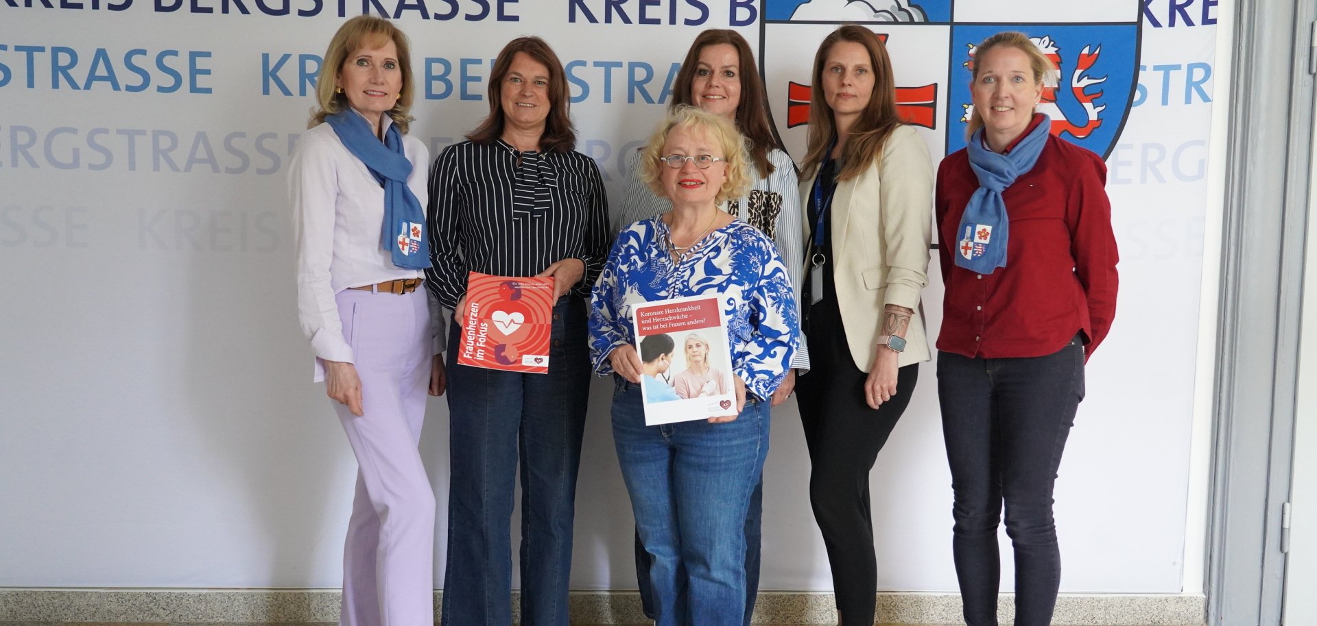 Die Erste Kreisbeigeordnete Angelika Beckenbach steht zusammen mit der Chefärztin für Gynäkologie und Geburtshilfe des Kreiskrankenhauses Bergstraße, Dr. Cordula Müller, sowie dem Präventionsteam des Kreises und dem Frauenbüro des Kreises vor dem Kreislogo.