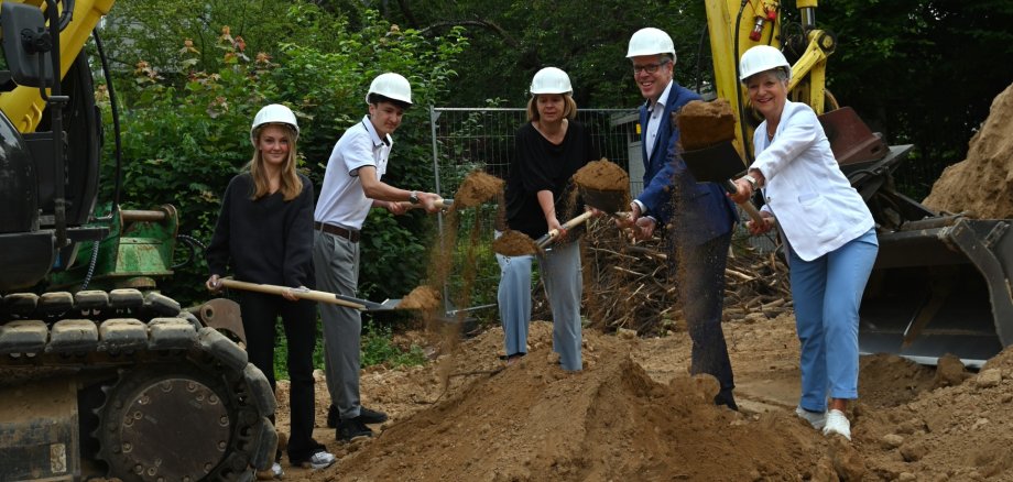Schulsprecherin Mila Seeger und Schulsprecher Bastian Wulff packen gemeinsam mit Schulleiterin Sylvia Meier, Landrat Christian Engelhardt und Bürgermeisterin Christine Klein an, um mit dem symbolischen Spatenstich den Bau der neuen Mensa zu beginnen.