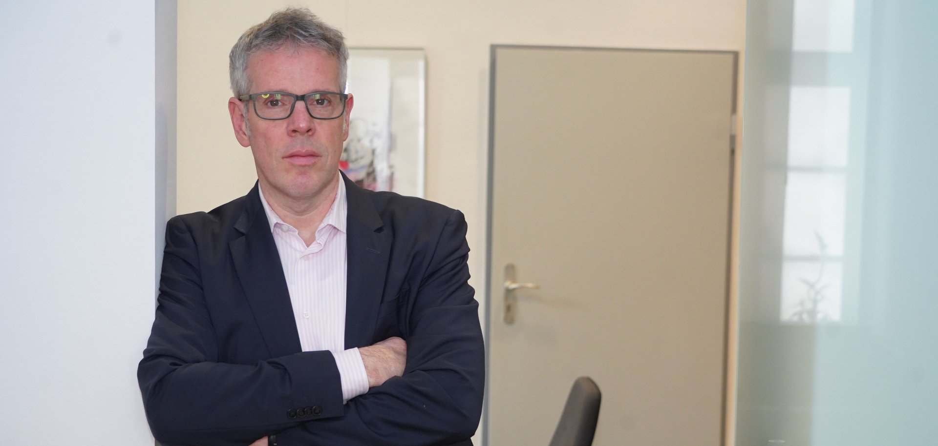 Landrat Christian Engelhardt steht mit verschränkten Armen an einem Türrahmen lehnend und schaut ernst in die Kamera.