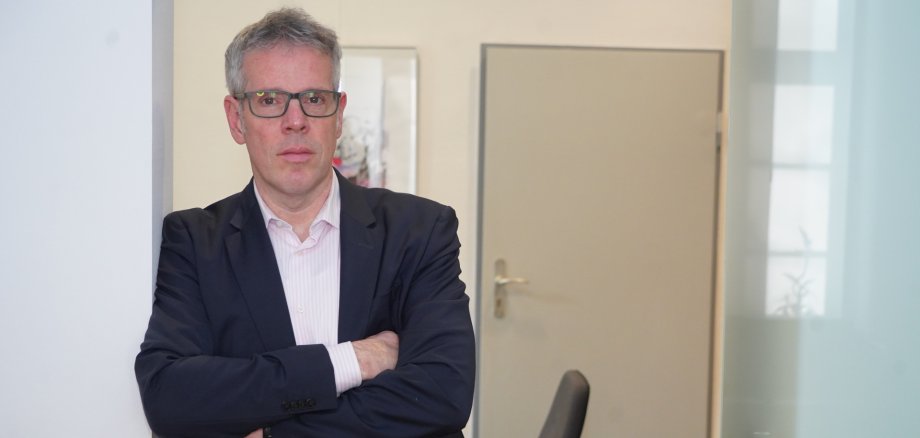 Landrat Christian Engelhardt steht mit verschränkten Armen an einem Türrahmen lehnend und schaut ernst in die Kamera.
